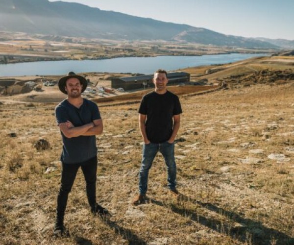 Scapegrace Distillery Founders Mark Neal and Daniel McLaughlin standing on grassy hill with their distillery in the distance